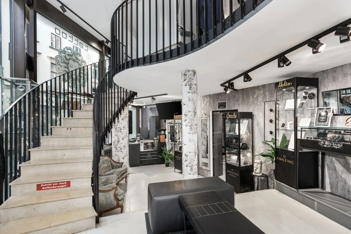 Ground-floor entrance area at Medusa Tattoo Munich with spiral staircase and premium jewelry displays